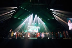 Большой банкетный зал со сценой и экранами, подготовленный для проведения корпоративного мероприятия.