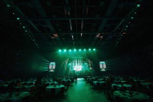 Вид сверху на банкетный зал с рассадкой гостей за круглыми столами на корпоративном вечере.