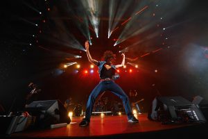 Артист на сцене в ярких световых лучах на корпоративном новогоднем мероприятии