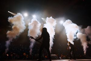 Гитарист исполняет соло в облаке сценического дыма на корпоративном шоу.