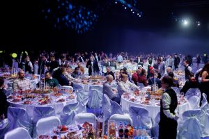 Просторный банкетный зал с изысканной рассадкой и динамическим световым оформлением для корпоративного ивента.