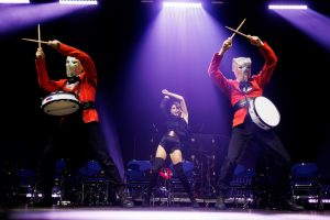 Артисты барабанного шоу выступают на большой сцене с яркими световыми эффектами на корпоративном празднике.