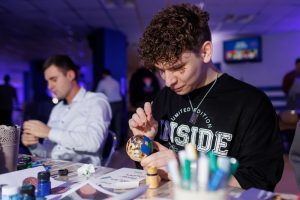 Гости участвуют в интерактивном мастер-классе на крупном корпоративном мероприятии с ярким световым оформлением.