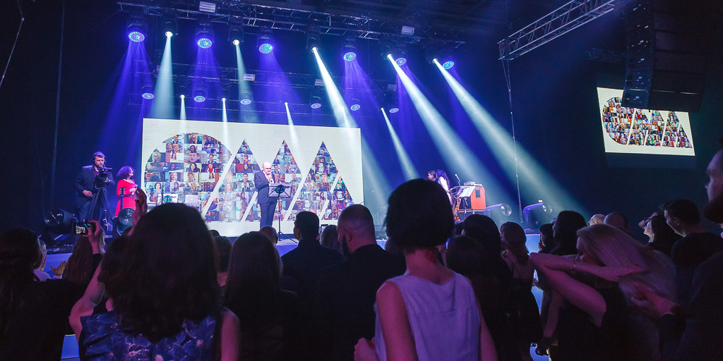 Сцена юбилея ОМА с логотипом компании, собранным из фотографий сотрудников